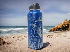 a blue water bottle sitting on top of a sandy beach