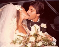 a bride and groom kissing in the back seat of a car with flowers on it