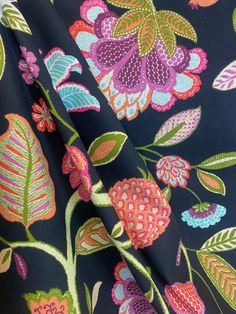 the fabric has colorful flowers on it and is very dark blue with pink, green, purple