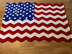 an american flag crocheted afghan sits on the floor in front of a wooden floor