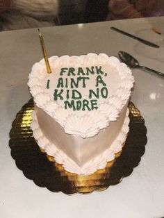 a white heart shaped cake with writing on it and a pen sticking out of the top