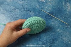 someone is crocheting a ball of yarn and knitting needles on a blue surface