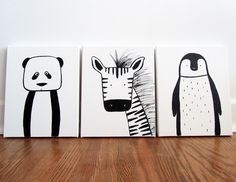 three black and white animal paintings on canvases, one with a zebra, the other an penguin