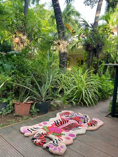 a tiger rug is laying on the ground in front of some trees and plants,