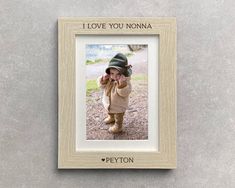 a wooden frame with a photo of a baby holding a cell phone to its ear