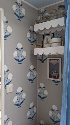 a bathroom with blue and white wallpaper and shelves above the toilet area, next to a shower curtain