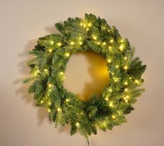 a christmas wreath with lights hanging on the wall