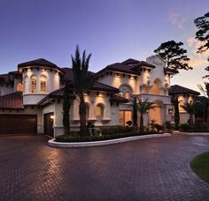 a large house with lots of windows and palm trees in front of it at dusk