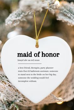 a white heart ornament hanging from a christmas tree with the words maid of honor written on it