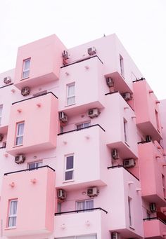 a tall pink building with lots of windows and balconies