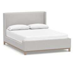 the bed is made up with white sheets and pillows on it's headboard