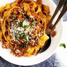 a white bowl filled with pasta covered in sauce and parmesan sprinkles