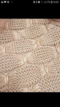 a close up of a knitted sweater with small flowers on it's side