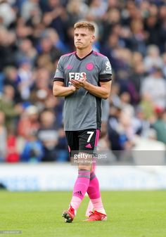 a soccer player is standing on the field with his hands clasped in front of him