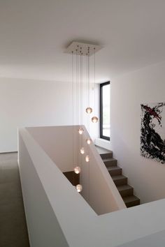 the light fixture is hanging from the ceiling above the stairs in this modern style house