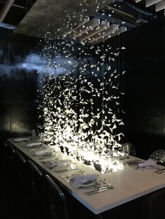 a long table with plates and silverware on it in front of a black wall