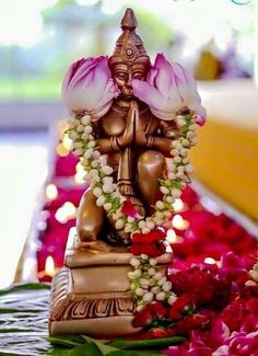 a small statue sitting on top of a table covered in flowers