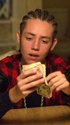 a young man sitting at a table looking at money