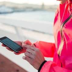 a woman in a pink jacket is looking at her cell phone