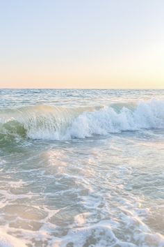 a person riding a surfboard on top of a wave in the ocean at sunset