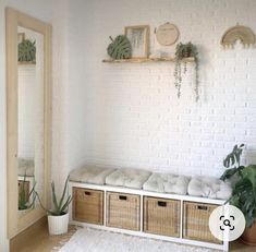 a white brick wall with some plants and baskets on the floor in front of it