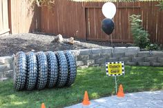 there is a bunch of tires on the ground in front of a yard with balloons