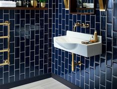 a blue tiled bathroom with gold fixtures and mirrors on the wall, along with a white sink