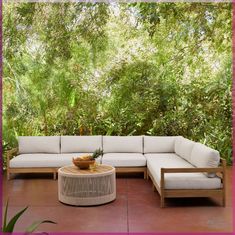 a white couch sitting on top of a wooden table next to a tree filled forest