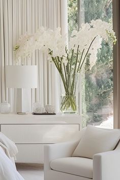 a bedroom with white furniture and flowers in a vase