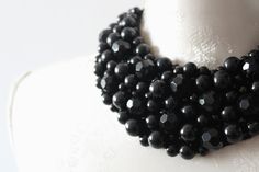 a black beaded necklace is displayed on a mannequin's neckline