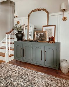 a large mirror sitting on top of a dresser next to a stair case with pictures