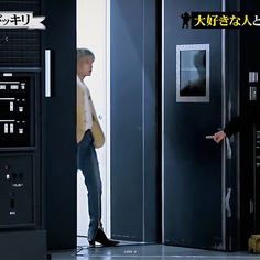 two men are standing in front of an elevator and one is pointing at the door