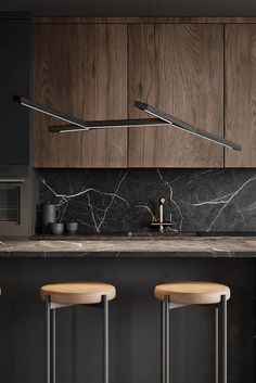 three stools in front of a kitchen counter with two lights hanging over the top