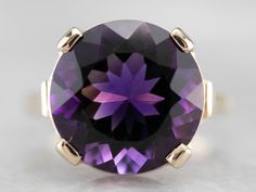 This amethyst cocktail ring is bold and beautiful! Set into a high profile, this amethyst is a deep royal purple, flashing with hues of violet and raspberry. The simple gold mounting puts the gem on full display, creating an instant showstopper! Metal: 14K Yellow Gold Gem: Amethyst 8.41 Carats Gem Measurements: 14 mm, Round Ring Size: 7.75 Marks: "14K" Stamped on the inside band