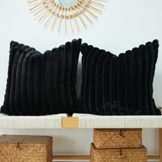 two black pillows sitting on top of a white shelf next to baskets and a mirror