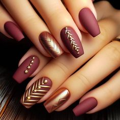 A rich, matte burgundy base with thin gold chevron stripes on a few accent nails. Small gold studs are placed along the chevron lines for extra dimension and a touch of metallic flair. This design feels warm, luxurious, and perfect for fall or winter. Matt Gold Nails, Burgundy Nails With Gold Foil, Burgundy Gold Nails, Fall Maroon Nails, Fall Nails Burgundy, Burgundy Fall Nails, Late Fall Nails, Basketball Nails