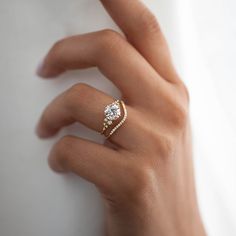 A woman's hand wears a set of wedding rings, featuring an engagement ring with a round diamond center accented by diamond clusters, and a pave wedding band that curves around the Snowdrift ring. Snowdrift Ring, Handcrafted Engagement Ring, Melanie Casey, The Bling Ring, Floating In Space, Cute Engagement Rings, Future Engagement Rings, Engagement Band, Curved Wedding Band