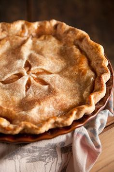 a pie sitting on top of a wooden table next to a white and blue napkin