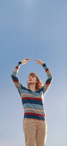 a woman standing on top of a hill with her hands in the air and looking up