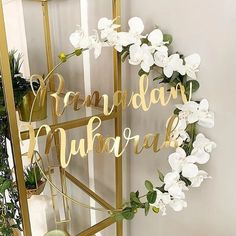 a white flower wreath sitting on top of a metal stand next to a planter