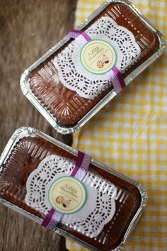 two chocolate cakes sitting on top of a table next to each other in tins