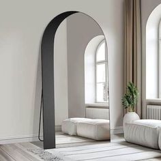 an arch shaped mirror in the middle of a living room with two white couches