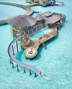 an aerial view of a water villa in the middle of the ocean with a slide going through it