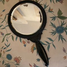 a magnifying glass sitting on top of a table next to a flowered wall