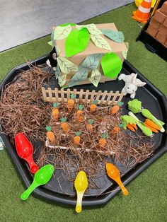 a black tray filled with plastic carrots and other vegetables on top of grass covered ground