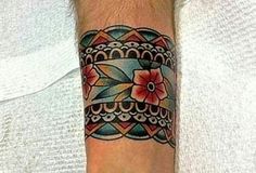 a person with a tattoo on their arm and wrist is wearing a white shirt that has a red flower in the center