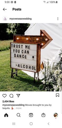 a sign that is on the ground in front of a tent with flowers and plants