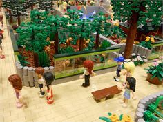 lego people are standing in front of a display case filled with plants and animals,