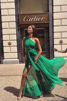 a woman in a green dress standing on the sidewalk