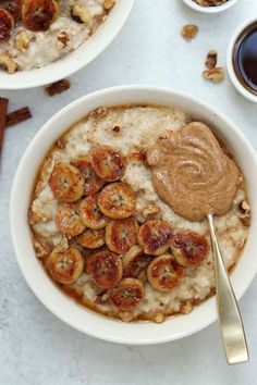 two bowls filled with oatmeal topped with bananas and nuts next to cups of coffee